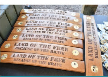 Engraved wooden clay-shoot station markers reading ‘Land of the Free, Because of the Brave’
